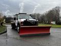 A 2009 Ford F-550 truck with a red snow plow attachment in the front