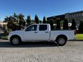 A white 2015 Nissan Frontier with a double cab parked on a street showing its side profile and chrome wheels