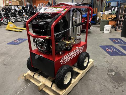 A red 2024 Magnum 4000 Hot Water Pressure Washer mounted on a wooden pallet featuring large wheels and various controls and attachments on its frame