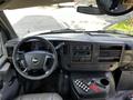 Interior view of a 2015 Chevrolet Express with a steering wheel dashboard audio controls and various buttons on the center console