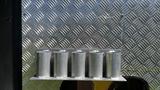 A metal rack holding five cylindrical containers attached to a surface with a diamond plate pattern