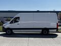 A 2022 Mercedes-Benz Sprinter van in white with a sleek design and side view showing its extended cargo area and black wheel rims