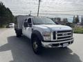 A 2010 Ford F-550 with a flatbed and a box truck attachment parked on the side of the road