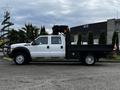 A 2015 Ford F-550 with a white cab and black flatbed parked on a lot