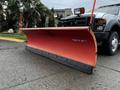 A 2009 Ford F-550 equipped with a large orange snow plow attached to the front