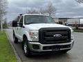 A white 2011 Ford F-250 SD pickup truck parked on the street featuring a black grille and chrome accents with a single cab and truck bed