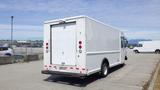 A white 2011 Ford Econoline van with a plain rear design and red brake lights parked in a lot