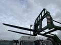A 2003 John Deere 790 with extended fork attachments raised in the air