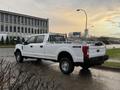 A white 2017 Ford F-350 Super Duty truck with a flatbed and metal rack is parked at an angle showing its side and rear view