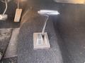 Gear shifter of a 1966 Ford Mustang with a chrome handle and a rectangular base on a textured carpeted floor