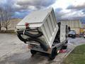 A 2007 Tennant Sentinel industrial cleaning machine featuring a large hopper and dual hoses for debris collection with a rear-mounted light and a black waste container attached