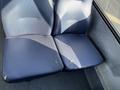 A close-up of a two-seat section in a vehicle showing blue fabric seats with visible wear and tear