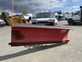 A red Western snow plow mounted on a truck with a silver cab and multiple lights on the roof