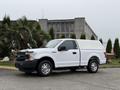 A 2018 Ford F-150 in white with a truck cap on the bed parked on a concrete surface