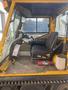 Interior of a yellow 2008 Camoplast SW 4S featuring a driver’s seat steering wheel and control panel with a fire extinguisher and liquid container visible