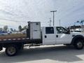 A 2010 Ford F-550 truck with a flatbed and a white enclosed cargo area attached to the back