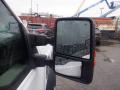 Close-up of the side mirror of a 2009 Ford F-450 SD with rain droplets on the glass and a blurred cityscape in the background