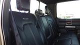 Interior view of the backseat of a 2017 Ford F-350 SD with black leather seats and a spacious design