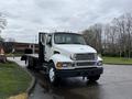 A 2008 Sterling Acterra flatbed truck with a white cab and chrome accents parked on a road