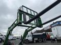 A green 2003 John Deere 790 tractor with a raised fork attachment positioned above the ground