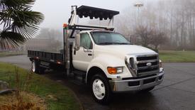 A 2008 Ford F-750 truck with a flatbed and a raised dump bed attachment in the front