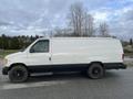 A white 2001 Ford Econoline van with black rims parked on a gravel road