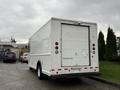 A white 2011 Ford Econoline cargo van with a rear roll-up door and red brake lights