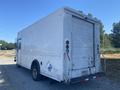 A 2008 Ford Econoline white delivery van with a boxy shape and a rear cargo door parked on gravel