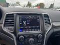 Interior dashboard of a 2018 Jeep Grand Cherokee featuring a touchscreen display with radio and media controls along with climate settings