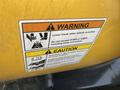 A warning and caution label on a yellow machine, providing instructions about lowering the blade and weight limits for the Fisner XV2 model