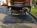 A 2020 Isuzu NPR with a lowered hydraulic lift gate for loading and unloading cargo