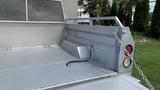 A silver 2013 RAM 2500 truck bed with an attached storage compartment and a chain securing the tailgate