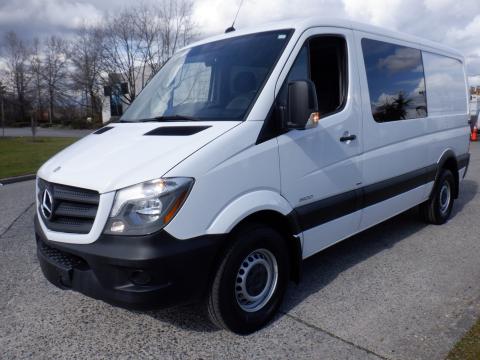 A white 2016 Mercedes-Benz Sprinter van with a sleek design and large windows standing on a paved surface