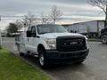 A 2014 Ford F-250 SD pickup truck in white with a black front grille and utility bed mounted in the back