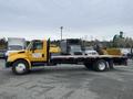 A yellow 2007 International 4300 flatbed truck with a black bed and visible wheels parked on a lot