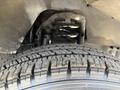 A close-up view of a tire and suspension system of a 2012 Ford Econoline showing the tread patterns and coil springs