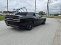 A black 2017 Dodge Challenger parked on a gravel surface showcasing its sleek design and sporty features