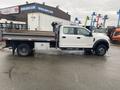 A white 2021 Ford F-550 truck with a flatbed and tool storage on the side