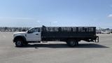 A 2019 Ford F-550 flatbed truck with a black bed and white cab parked in an empty lot