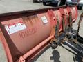 A close-up of a snow plow attachment with visible hydraulic components and a model number 10M502