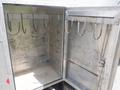 An open aluminum storage compartment with several metal hooks mounted on the interior walls