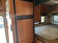 A 2012 Ford Econoline interior featuring wooden cabinets a refrigerator and a bed area