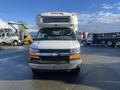 A 2012 Chevrolet Express van with a white exterior and a distinctive large front grill and headlights centered on the vehicle's body