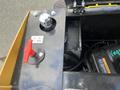 A close-up view of the control panel of a 2024 AGT Mini Excavator featuring a red lever and a metal cap on a black surface