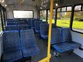 Interior view of a 2017 Chevrolet Express bus featuring blue patterned seats arranged in rows with a light gray floor and yellow support poles