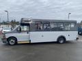 2017 Chevrolet Express bus with a white and gray exterior featuring large windows and a step for entry