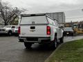 A white 2019 Chevrolet Colorado pickup truck with a cap on the bed is parked at an angle showing the rear and side views