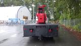 A 2010 International 4300 truck with a red crane mounted on the back, featuring a flatbed design and textured black surface