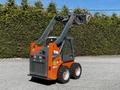 A 2017 Gehl R105 skid steer loader with a raised arm and bucket attached on a gravel surface