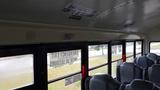 Interior view of a 2015 International PC105 school bus with empty gray seats and emergency exit signs on the walls